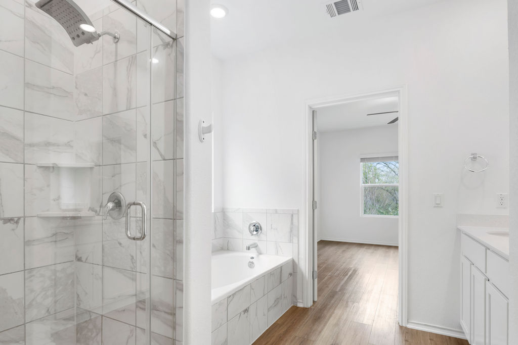 1205 Sweetspire Street Leander, TX 78641 - Photo 5 of 31 Full bath featuring a garden tub, vanity, light wood-style flooring, and a marble finish shower
