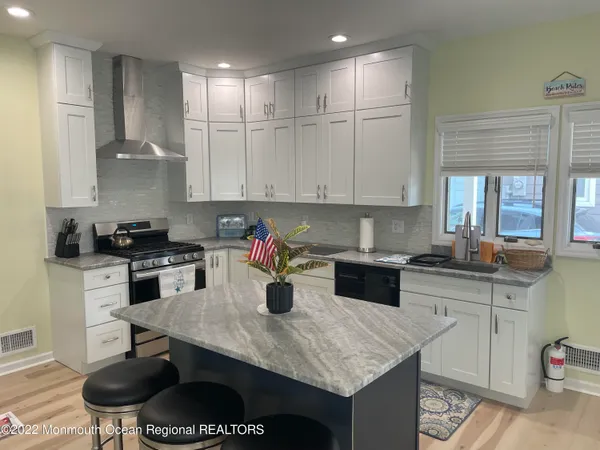 a kitchen with a stove a sink a refrigerator and chairs