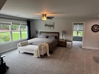 a bed sitting in a spacious bedroom next to a window