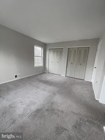 a view of an empty room with a window and chandelier fan