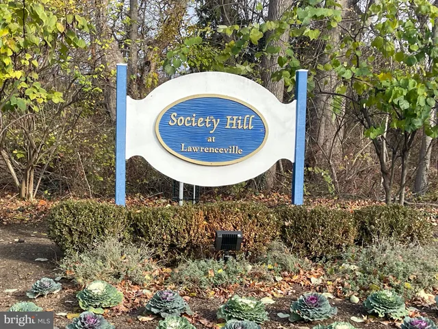 a sign of golf club on a stone wall under a large tree
