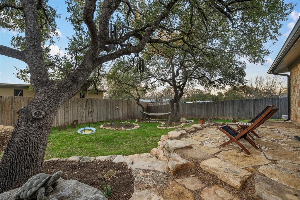 2210 Red Fox Road Austin, TX 78734 - Photo 22 of 40 A spacious backyard retreat features mature shade trees, a stone patio, and lush green lawn.