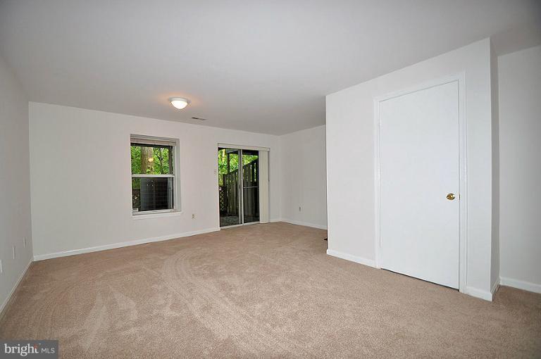 a view of an empty room with window and kitchen view