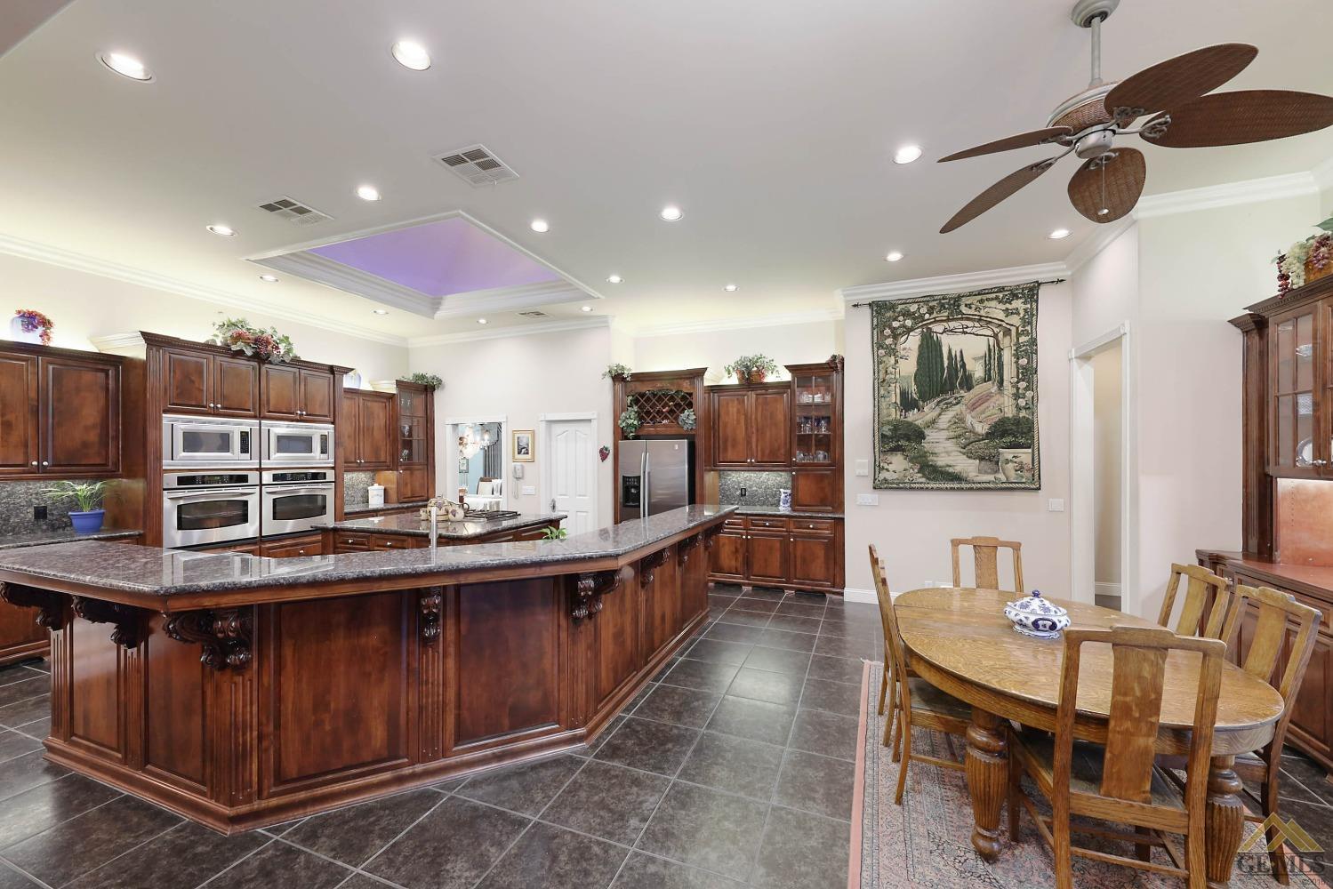 Undisclosed Address Bakersfield, CA 93312 - Photo 4 of 48 a kitchen with stainless steel appliances kitchen island granite countertop a table chairs in it and wooden floors