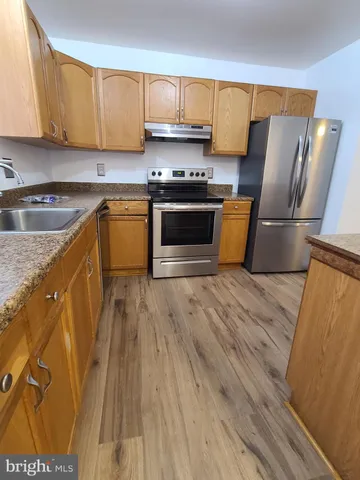 a kitchen with wooden floors and stainless steel appliances
