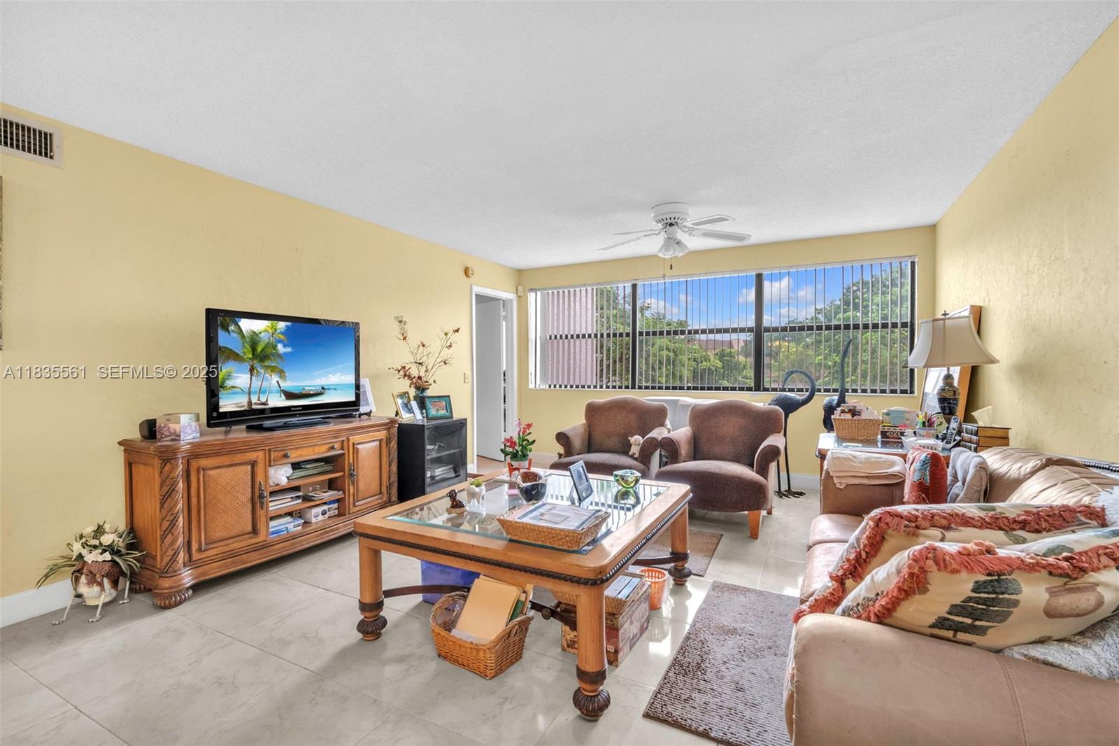 10400 Northwest 30th Court, Unit 305 Sunrise, FL 33322 - Photo 7 of 26 a living room with furniture a flat screen tv and a floor to ceiling window