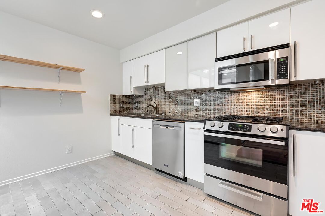 1013 21st Street, Unit B Santa Monica, CA 90403 - Photo 12 of 28 a kitchen with stainless steel appliances white cabinets and granite counter tops