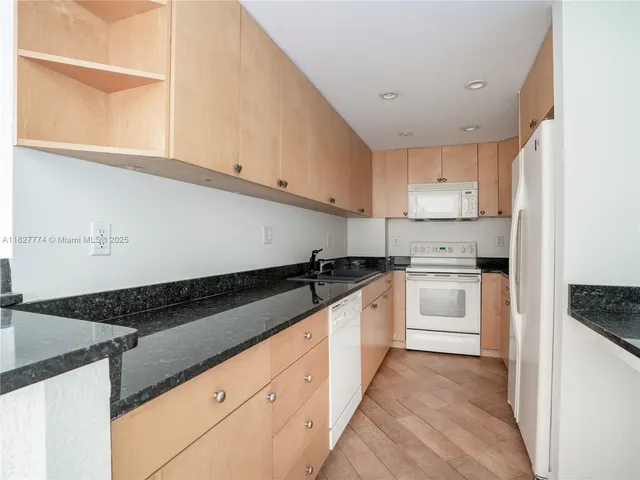 a kitchen with granite countertop white cabinets and white appliances