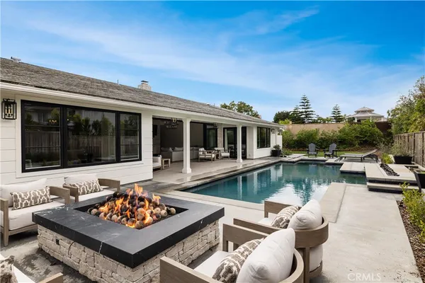 a view of house with swimming pool and couches chairs