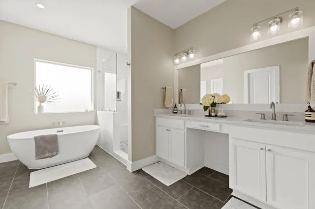 a spacious bathroom with a double vanity sink a mirror a bathtub and next to a window