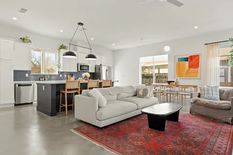 a living room with stainless steel appliances kitchen island granite countertop a sink a stove a dining table and chairs