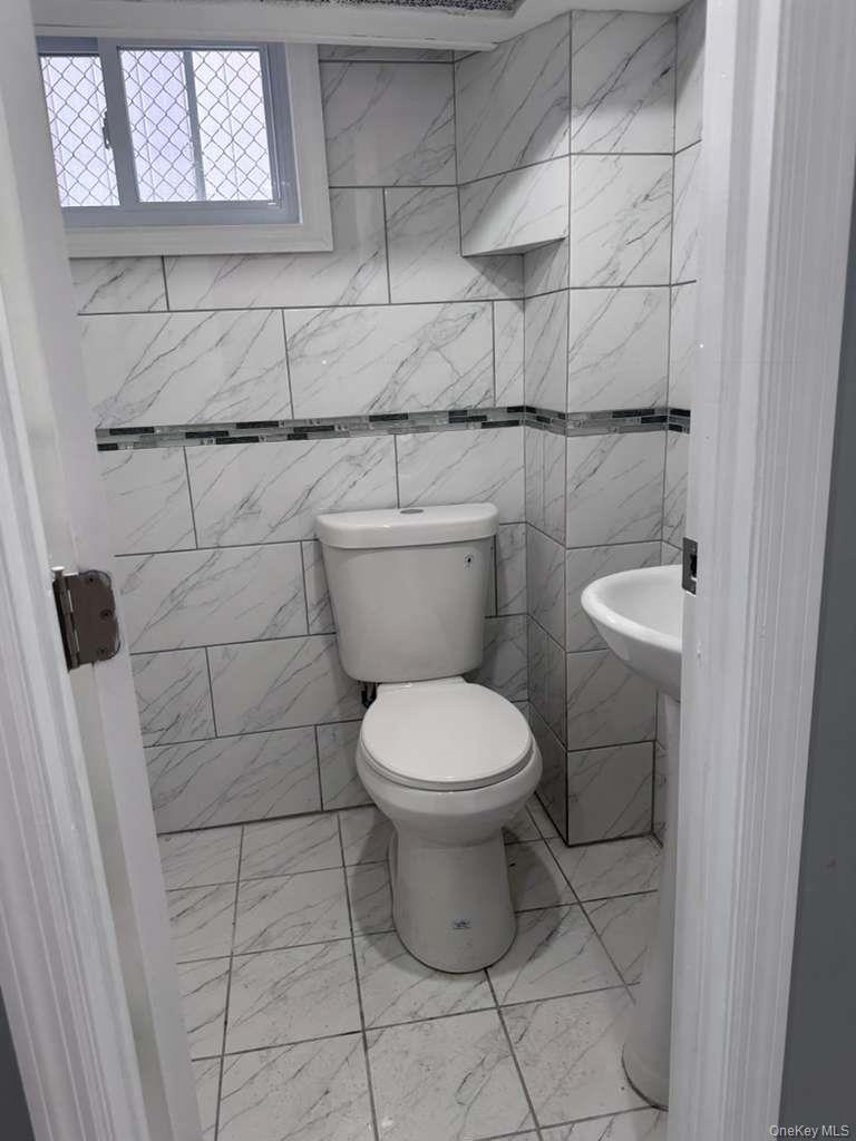 114-06 Inwood Street Queens, NY 11436 - Photo 15 of 18 Bathroom featuring tile walls and light marble finish flooring