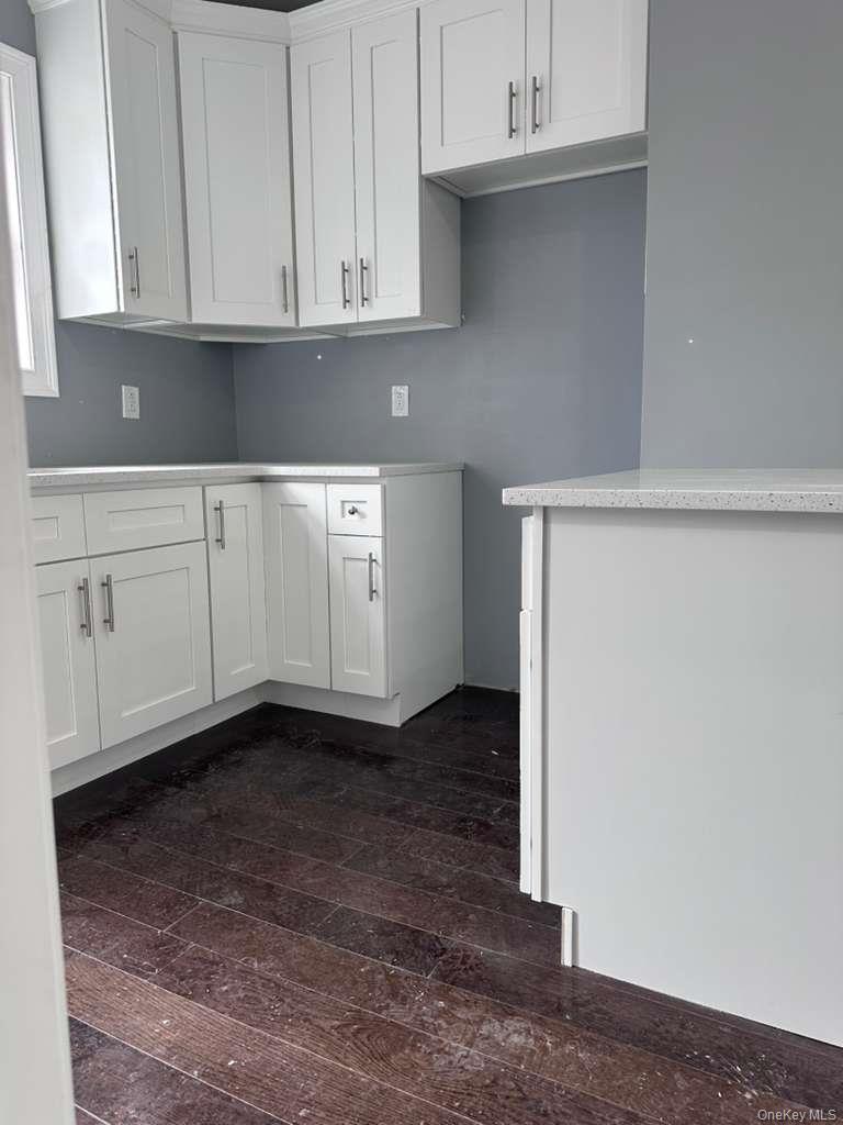 114-06 Inwood Street Queens, NY 11436 - Photo 4 of 18 Kitchen featuring white shaker-style cabinetry, light speckled countertops, and dark wood-finish flooring