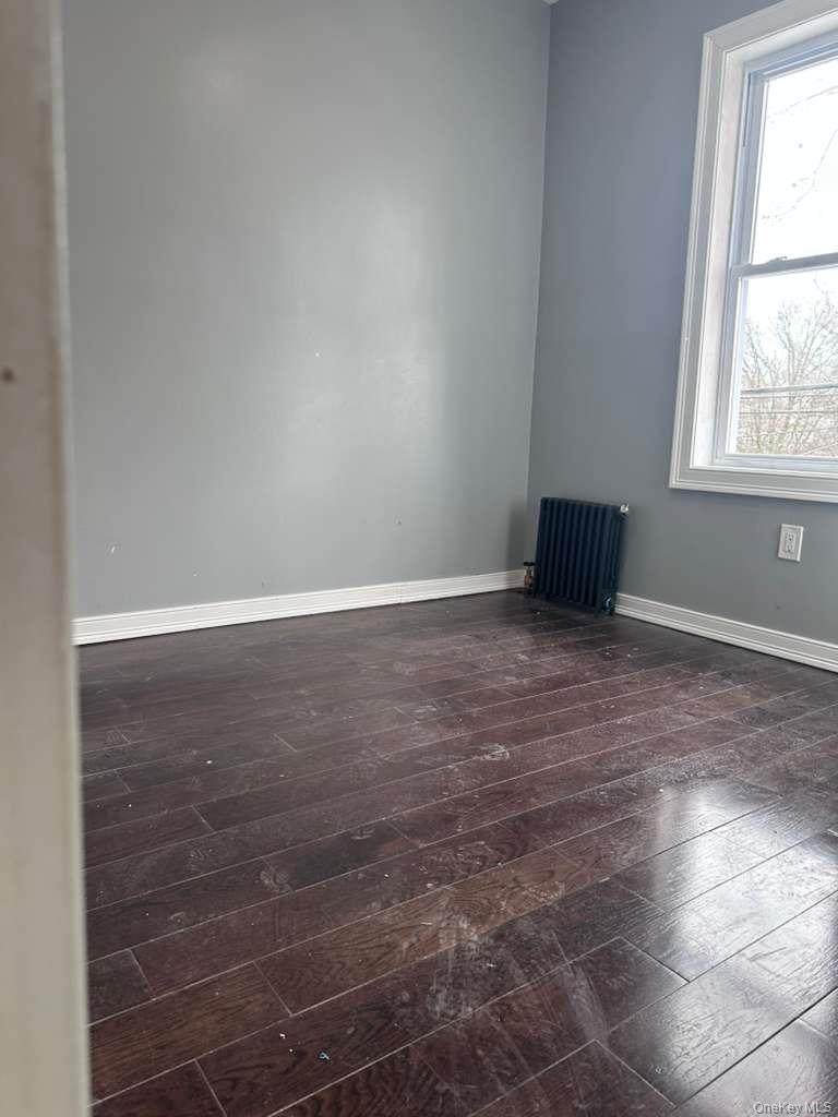 114-06 Inwood Street Queens, NY 11436 - Photo 6 of 18 Spare room featuring dark wood finished floors and radiator heating unit