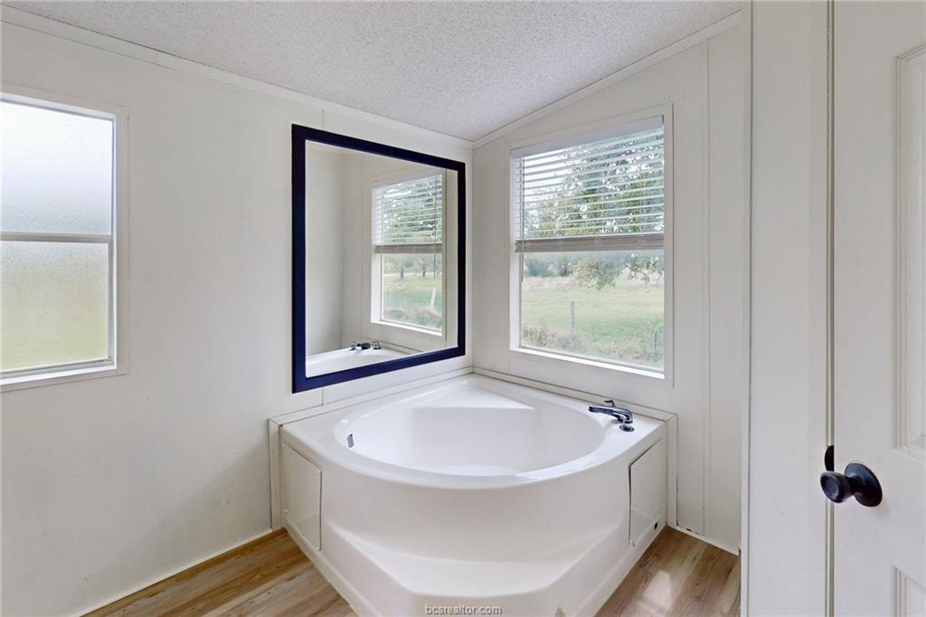 11459 Winstead Lane Calvert, TX 77837 - Photo 27 of 41 Corner soaking tub with deck-mounted faucet and wood-finish flooring