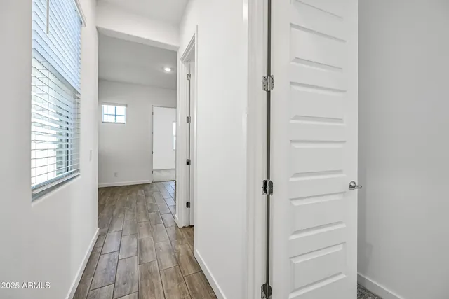 a view of a hallway with wooden floor and a bathroom