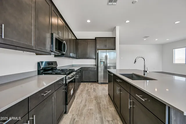 a kitchen with stainless steel appliances granite countertop a sink stove refrigerator and cabinets
