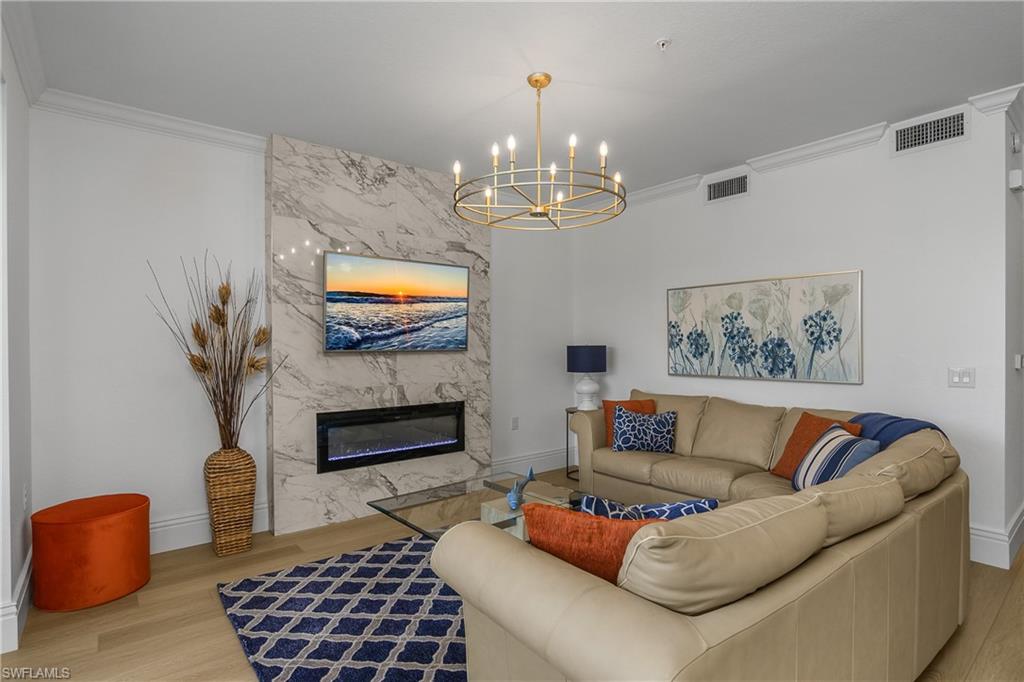 9554 Trevi Court, Unit 4727 Naples, FL 34113 - Photo 11 of 50 a living room with furniture a fireplace and a chandelier