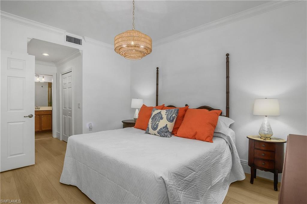 9554 Trevi Court, Unit 4727 Naples, FL 34113 - Photo 17 of 50 a bedroom with a bed and wooden floor