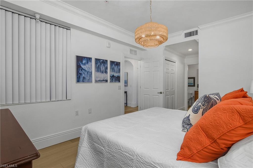 9554 Trevi Court, Unit 4727 Naples, FL 34113 - Photo 18 of 50 a bedroom with a bed and a chandelier
