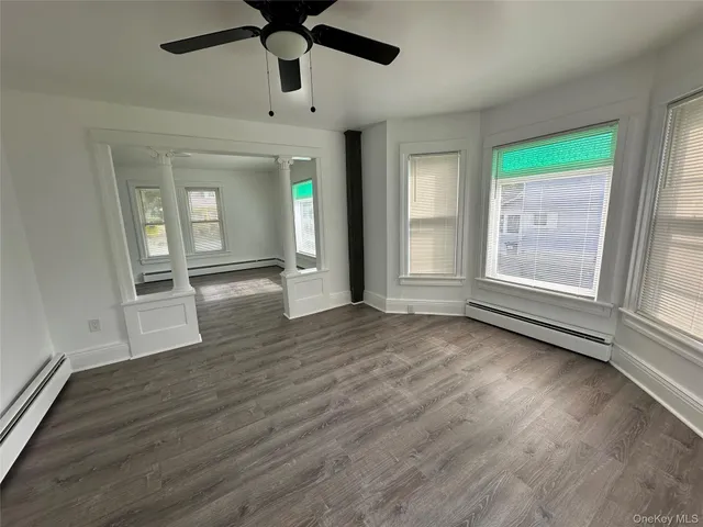 an empty room with wooden floor fan and windows