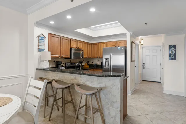 a kitchen with stainless steel appliances granite countertop a refrigerator a stove a sink a dining table and chairs with wooden floor