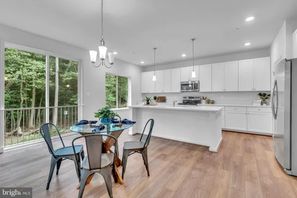 a kitchen with stainless steel appliances granite countertop a stove a refrigerator a kitchen island a dining table and chairs