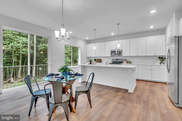 a kitchen with stainless steel appliances granite countertop a stove a refrigerator a kitchen island a dining table and chairs