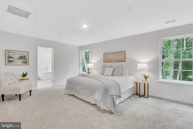 a spacious bedroom with a bed a table and windows