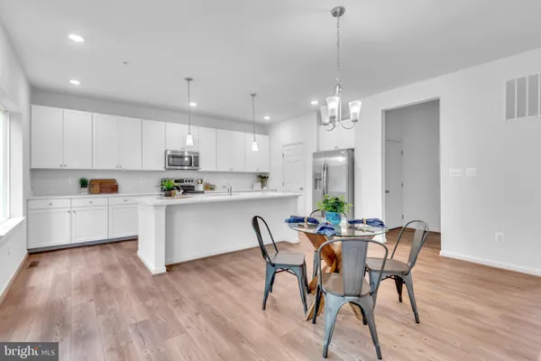 a kitchen with dining table wooden floor stainless steel appliances and cabinets