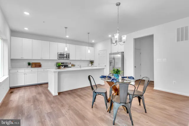 a kitchen with dining table wooden floor stainless steel appliances and cabinets