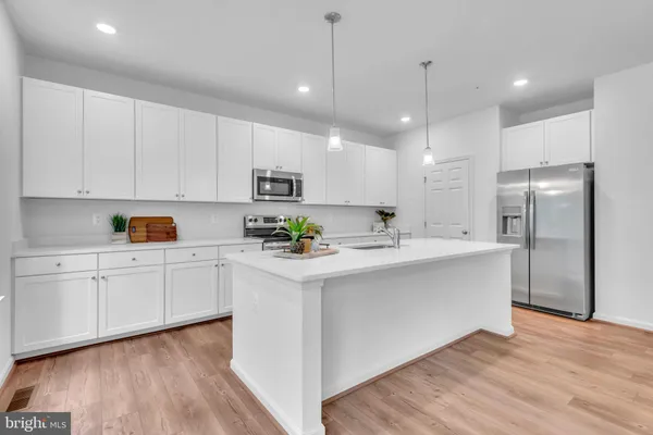 a kitchen with stainless steel appliances granite countertop a refrigerator a sink dishwasher a stove and white cabinets with wooden floor