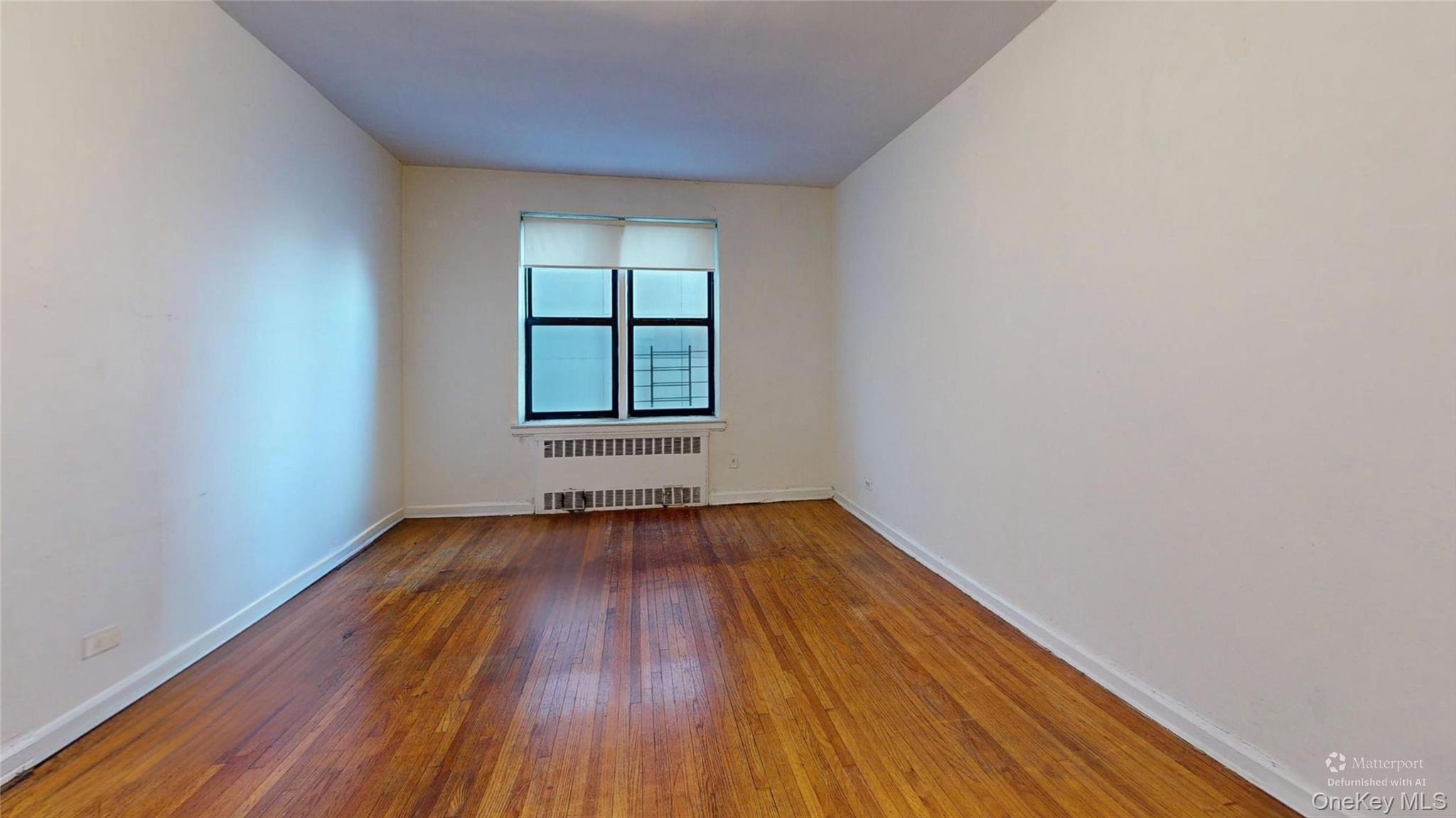 123-35 82nd Road, Unit 3Q Queens, NY 11415 - Photo 12 of 15 an empty room with wooden floor and windows