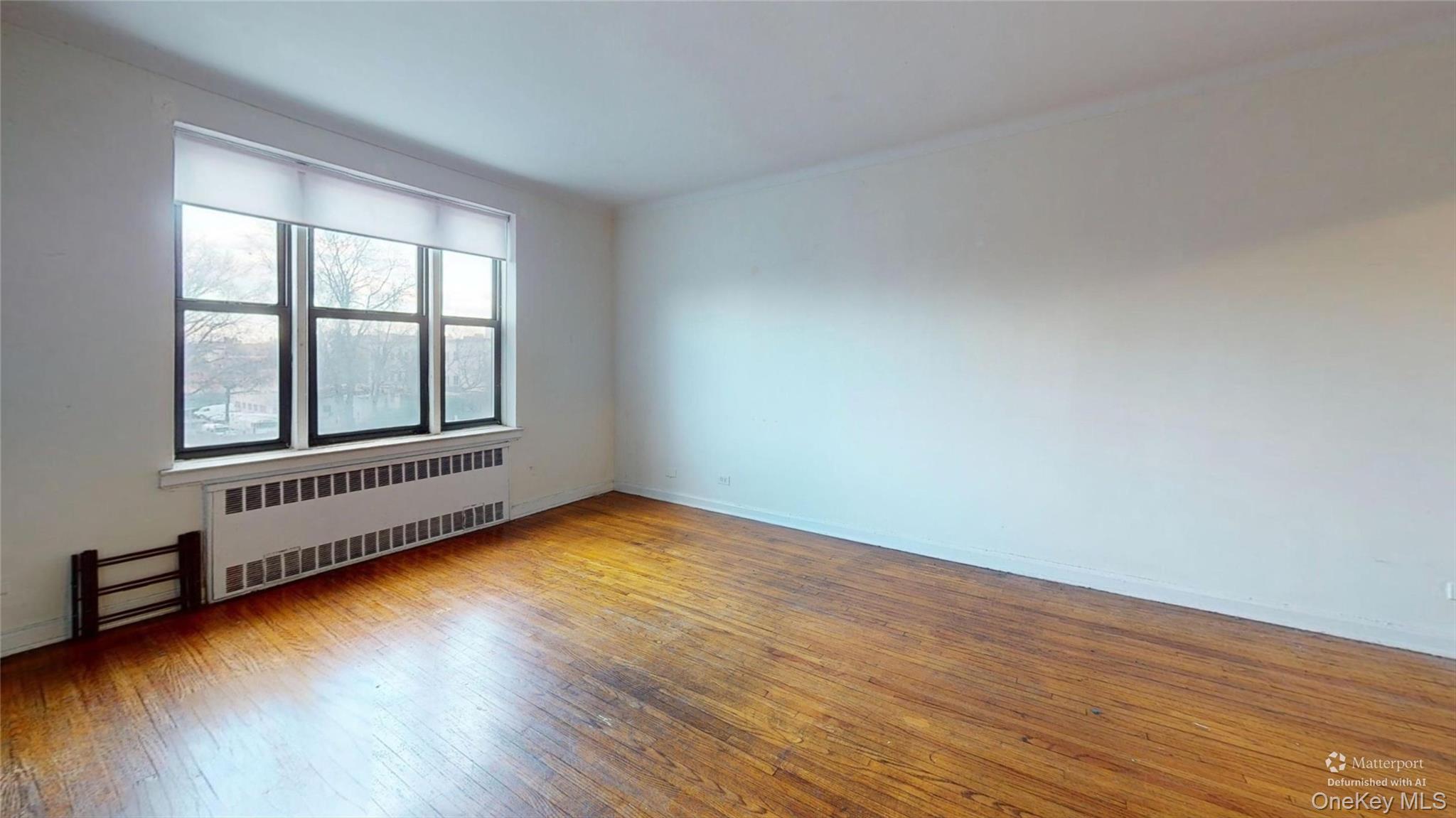 123-35 82nd Road, Unit 3Q Queens, NY 11415 - Photo 4 of 15 a view of an empty room with wooden floor and a window