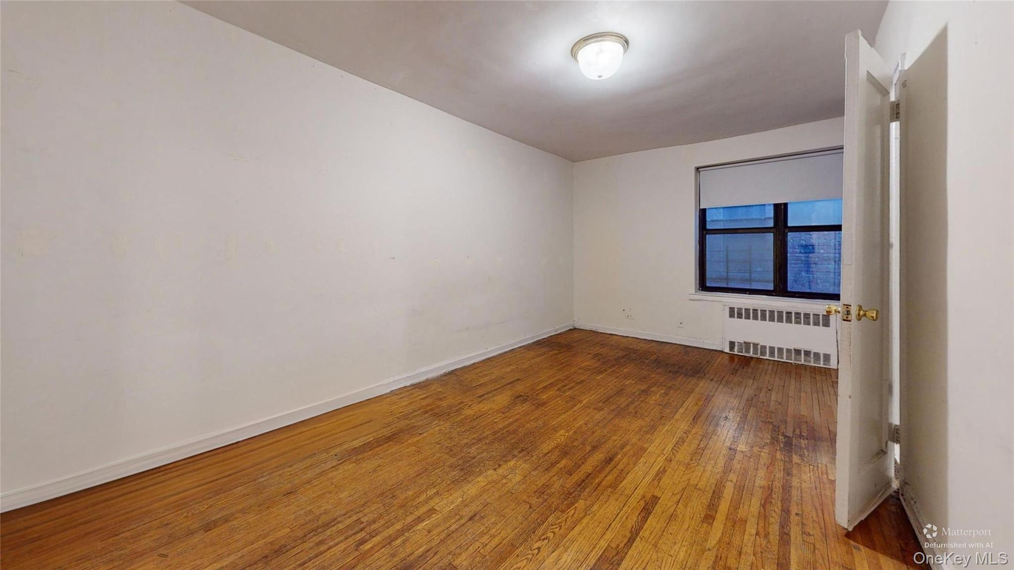 123-35 82nd Road, Unit 3Q Queens, NY 11415 - Photo 8 of 15 an empty room with wooden floor and window