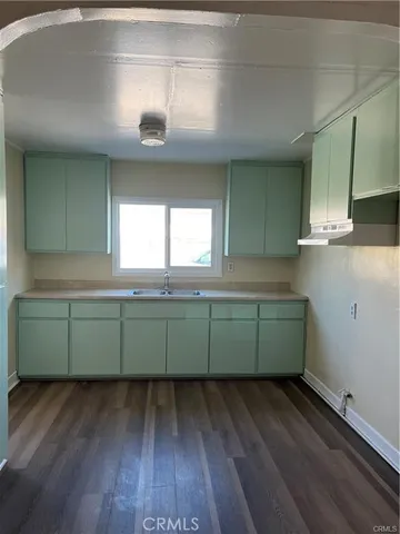 a kitchen with green walls and a hard wood floor