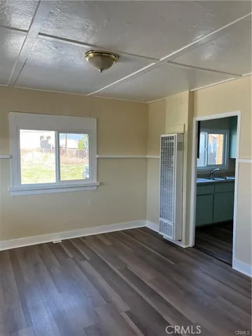 an empty room with wooden floor and a kitchen