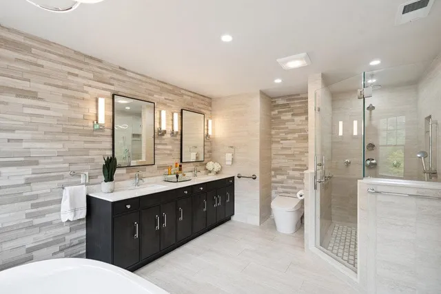 a bathroom with a double vanity sink a toilet and a shower