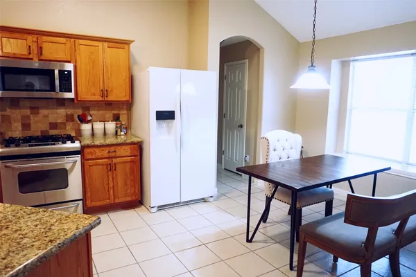 a kitchen with stainless steel appliances kitchen island granite countertop a sink a microwave cabinets and a dining table