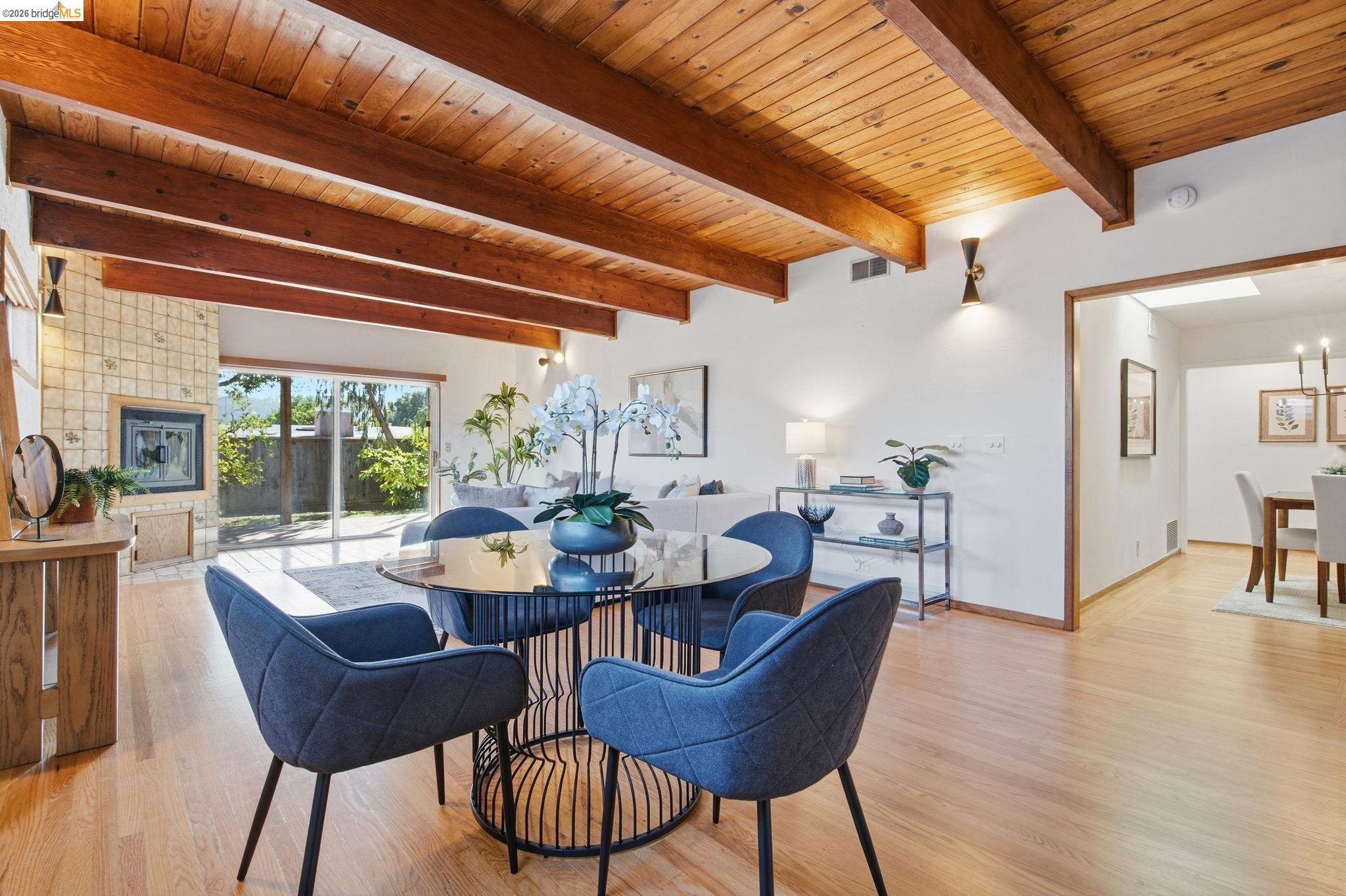 4522 Santa Rita Road El Sobrante, CA 94803 - Photo 30 of 58 Exposed wood beam ceiling, wood-finish flooring, stone-clad fireplace, and sliding glass doors