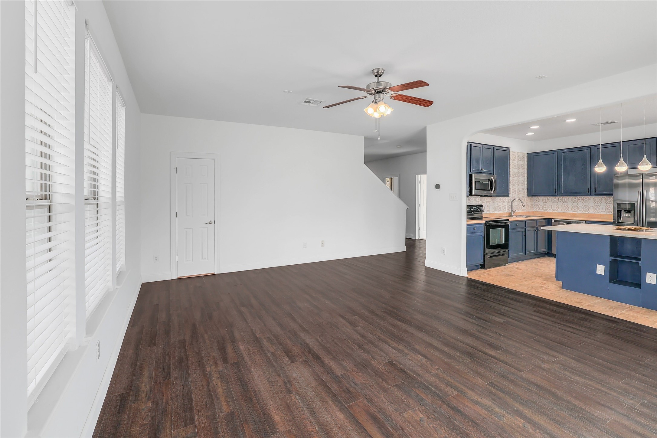 203 Ran Road Leander, TX 78641 - Photo 9 of 31 Rich wood-look flooring anchors this open living space adjacent to a modern kitchen.