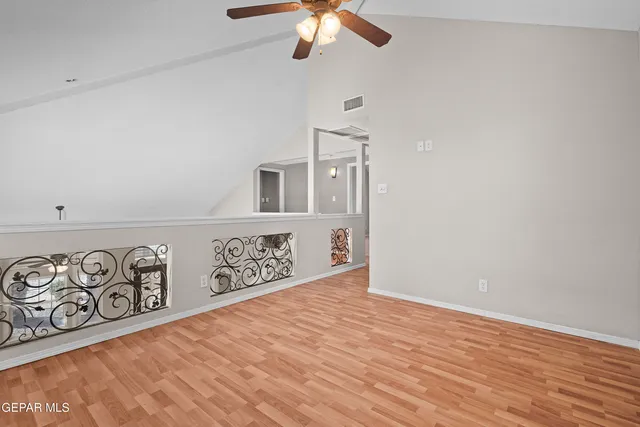 an empty room with chandelier fan and windows