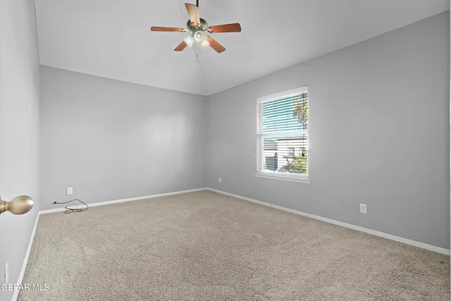 a view of an empty room with a chandelier fan