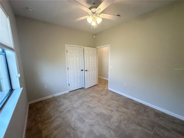 an empty room with closet and a chandelier fan