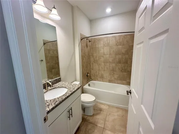 a bathroom with a granite countertop sink toilet mirror and shower