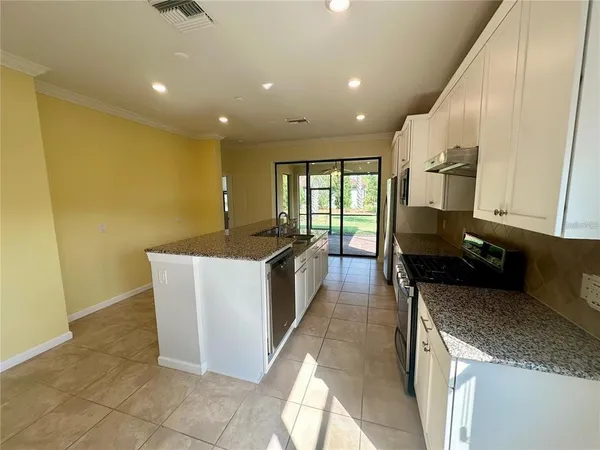 a large kitchen with stainless steel appliances granite countertop a sink a stove and a refrigerator