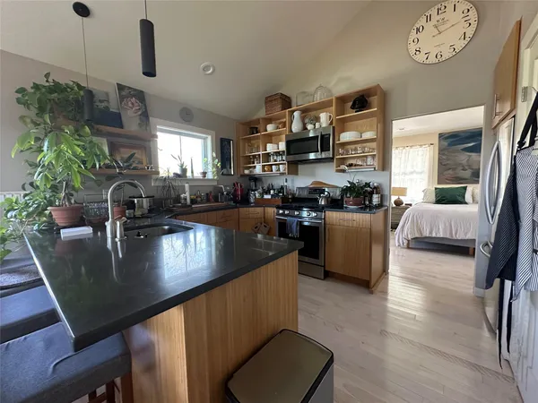 a kitchen with stainless steel appliances granite countertop a sink a stove and a dining table with wooden floor