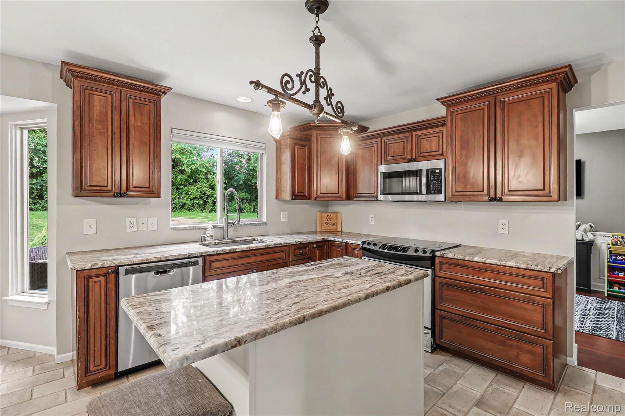 2548 Empire Court Rochester, MI 48309 - Photo 11 of 40 Kitchen featuring a central island, wood cabinetry, stone countertops, stainless steel appliances, and tile flooring