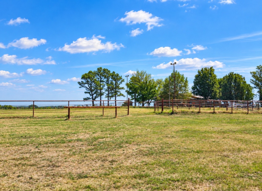 12526 3520th Road Seminole, OK 74868 - Photo 27 of 42 Expansive grassy area with perimeter fencing, mature trees, and a distant body of water