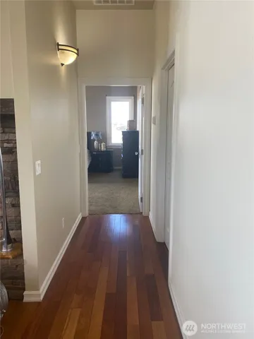 a view of a hallway with wooden floor and a bathroom